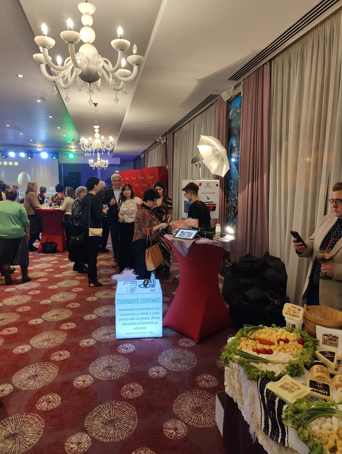 Participanți lângă cabina foto inFUNity și standuri de brand la un eveniment corporate